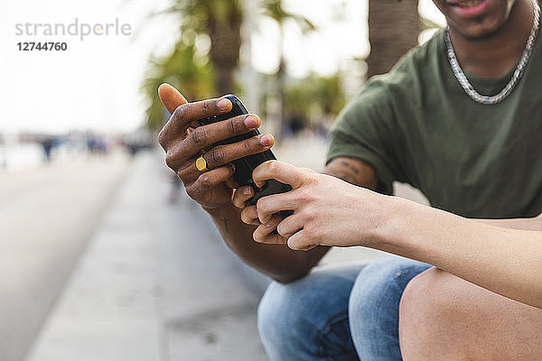 Hands of multicultural young couple holding smartphone  close-up