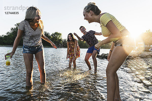 Group of happy friends having fun in a river at sunset