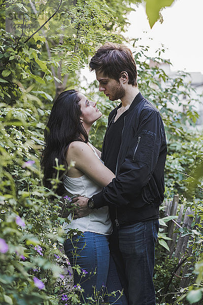 Young couple in love standing in shrubbery