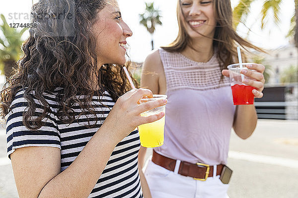 Two happy female friends enjoying a fresh slush