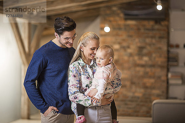 Happy young parents spending time at home with their baby girl