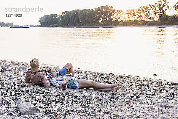 Young couple relaxing at the riverbank at sunset