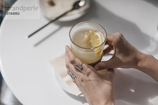 Woman holding glass of ginger lemon tea
