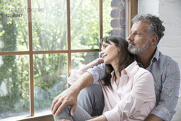 Mature couple sitting on window sill  looking out of window