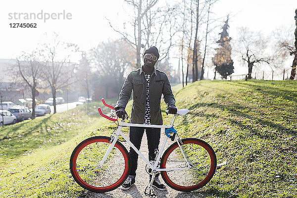 Young holding bicycle in park