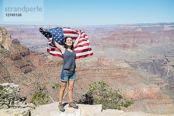 USA  Arizona  smiling woman with American flag at Grand Canyon National Park