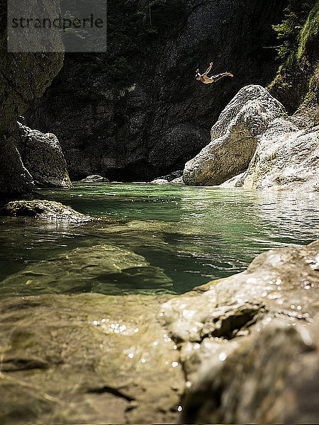 Man jumping from rock into brook