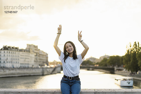 France  Paris  portrait of happy young woman at river Seine at sunset