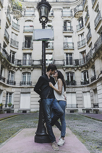 France  Paris  young couple in love standing at street lantern in front of urban building
