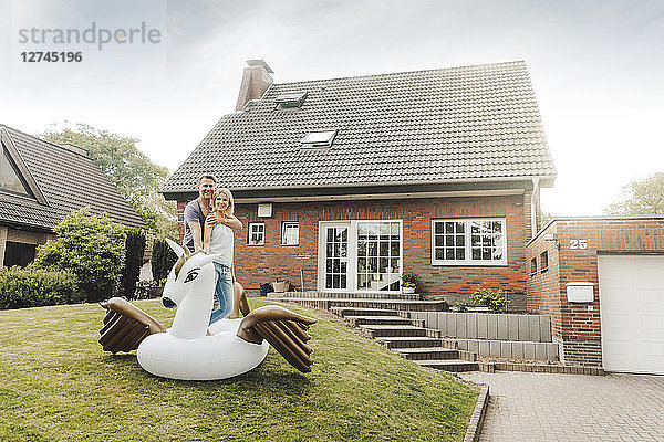 Portrait of smiling mature couple with inflatable pool toy in garden of their home