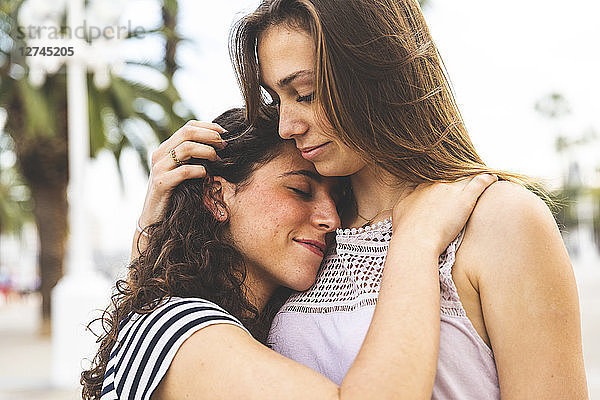 Two female friends embracing and hugging outdoors