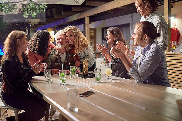 Happy friends clapping  celebrating on patio at night