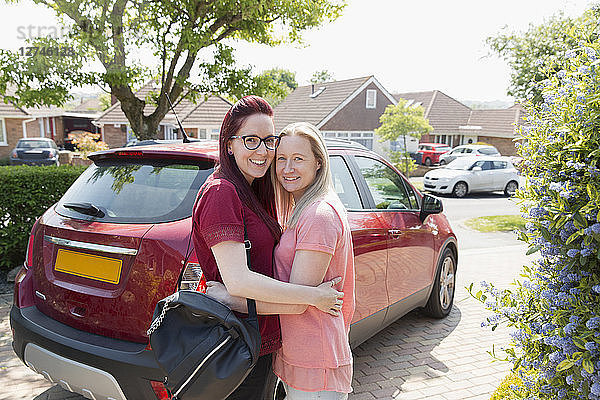 Portrait affectionate lesbian couple hugging in driveway