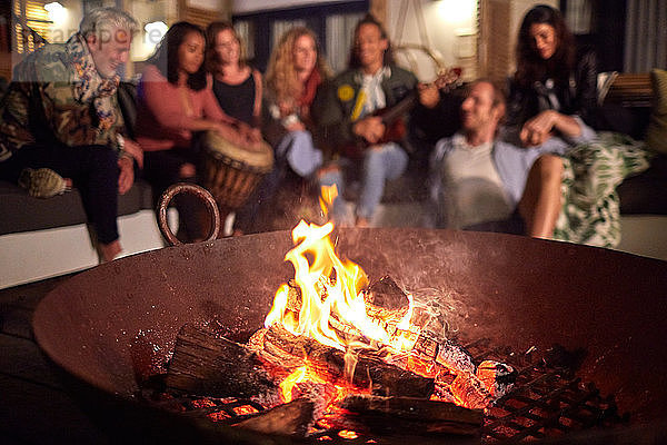 Friends hanging out  playing music on patio next to fire pit