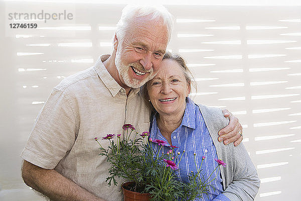 Portrait happy active senior couple with flowerpots