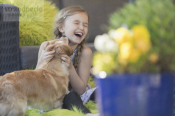 Dog kissing laughing girl on patio