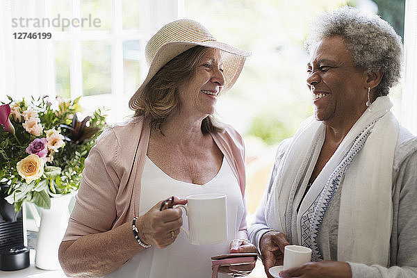 Happy senior women friends enjoying coffee
