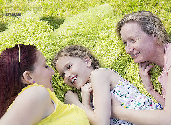 Affectionate lesbian couple and daughter laying in grass