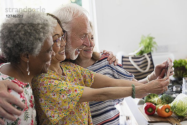 Happy senior friends taking selfie with camera phone