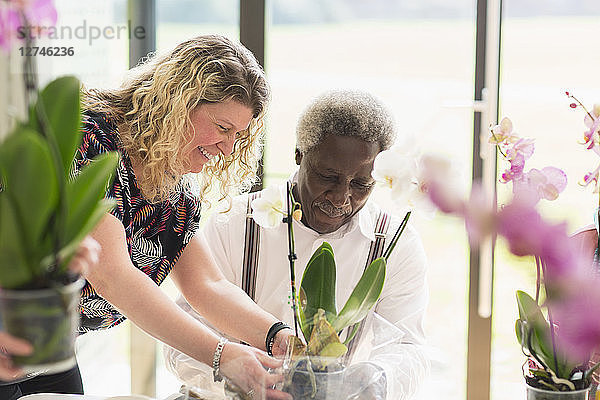 Female instructor helping active senior man in flower arranging class