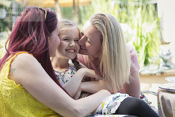 Affectionate lesbian couple kissing daughter