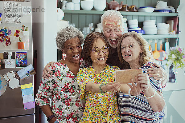 Happy  playful active seniors taking selfie with camera phone  making silly faces