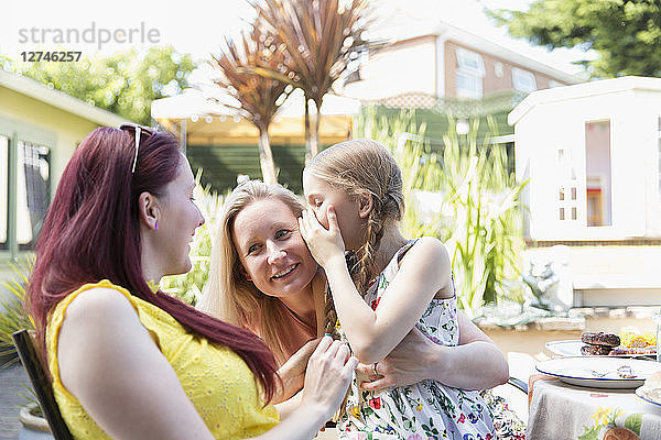 Affectionate lesbian couple holding daughter on sunny patio