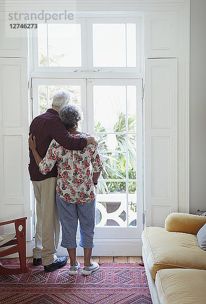 Serene senior couple looking out living room window