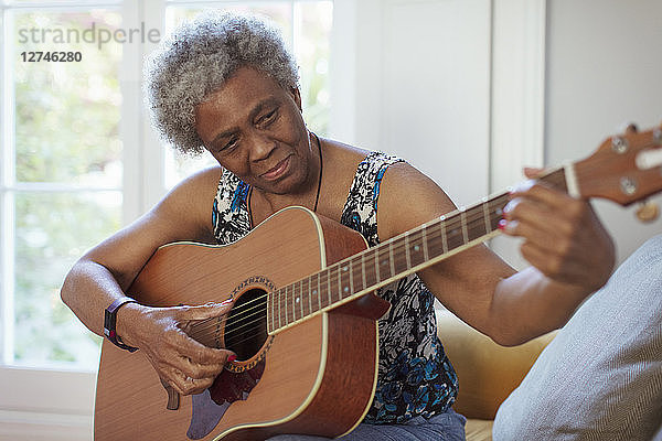 Active senior woman playing guitar