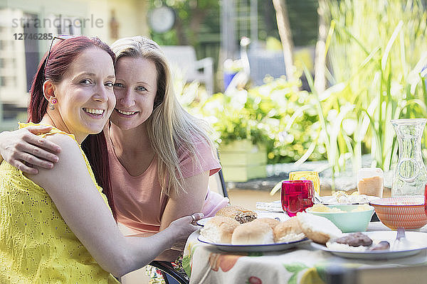 Portrait affectionate lesbian couple enjoying lunch on patio