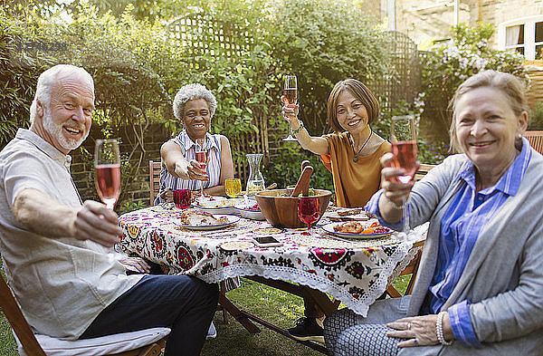 Portrait smiling  confident active senior friends drinking rose wine and enjoying lunch at patio table