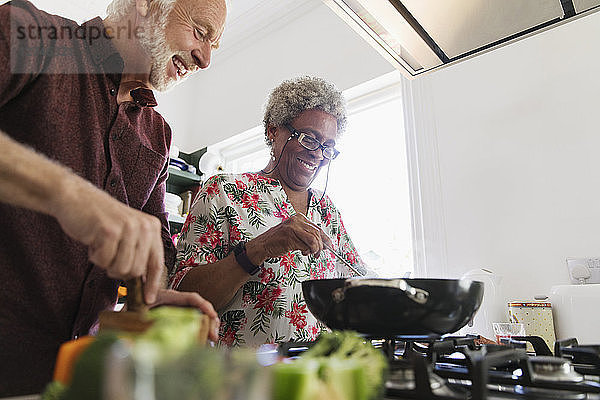 Active senior couple cooking in kitchen