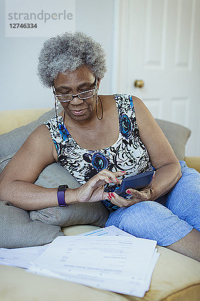 Senior woman with calculator reviewing bills