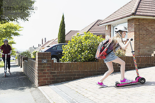 Girl riding scooter in sunny driveway