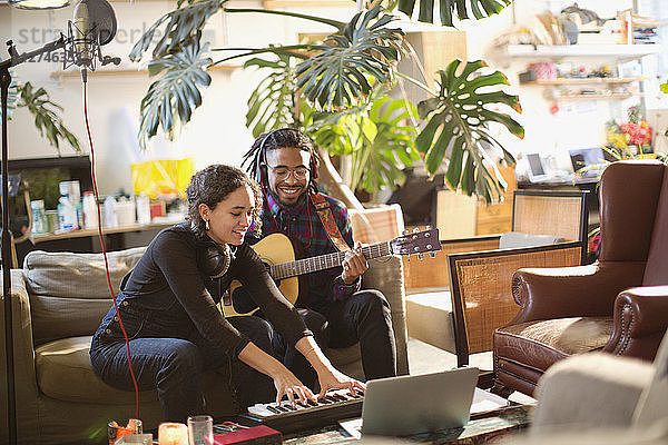 Junger Mann und Frau nehmen Musik auf  spielen Gitarre und Klavier in einer Wohnung