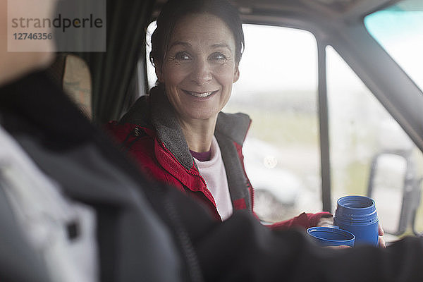 Lächelnde Frau trinkt Kaffee im Wohnmobil