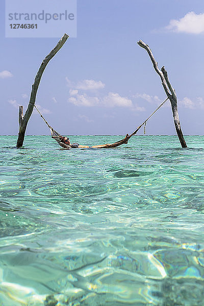 Junge Frau in der Hängematte über dem ruhigen blauen Ozean  Malediven  Indischer Ozean