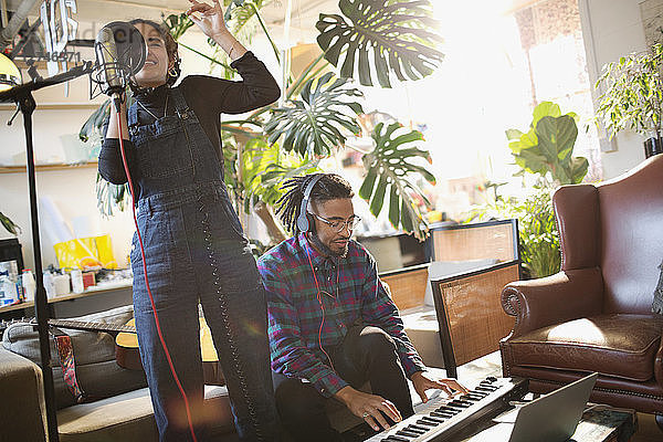 Junger Mann und Frau nehmen Musik auf  singen und spielen Klavier in einer Wohnung