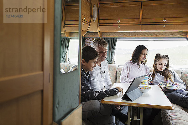 Familie entspannt sich  isst und benutzt ein digitales Tablet im Wohnmobil