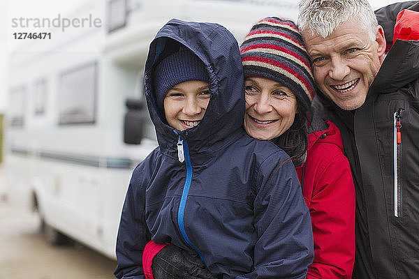 Porträt einer liebevollen Familie in warmer Kleidung  die sich außerhalb des Wohnmobils umarmt