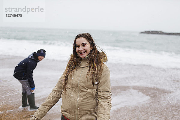 Lächelndes Teenager-Mädchen am winterlichen Meeresstrand