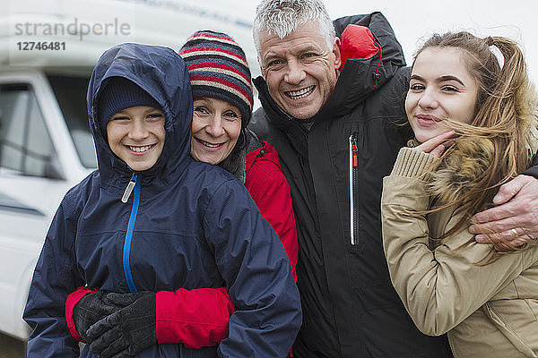 Porträt liebevolle glückliche Familie in warmer Kleidung vor Wohnmobil