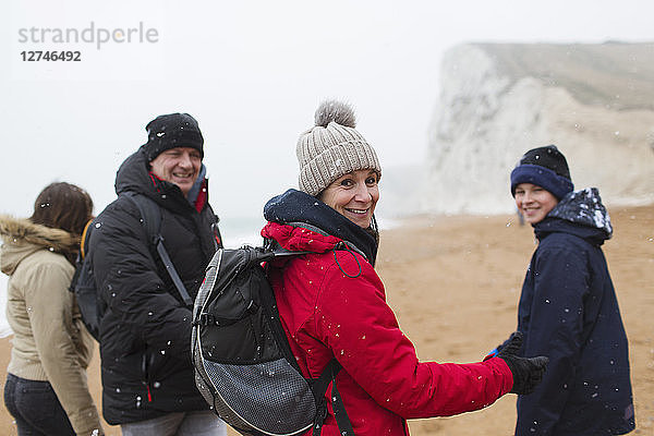 Portrait lächelnde Familie in warmer Kleidung am verschneiten Winterstrand