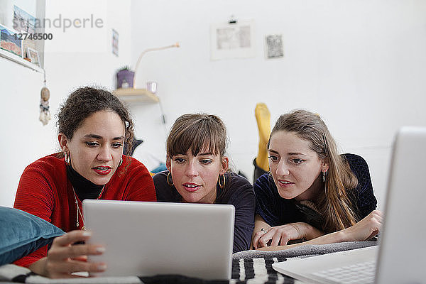 Junge Freundinnen teilen sich ein digitales Tablet auf dem Bett
