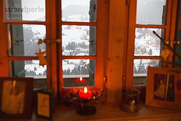 Weihnachtskerze im Fenster mit Blick auf eine ruhige Schneelandschaft  Forclaz  Schweiz