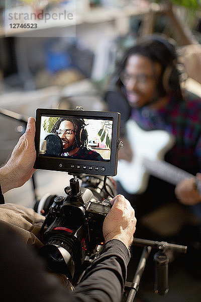 Videofilmer filmt jungen männlichen Musiker beim Singen und Gitarrenspielen