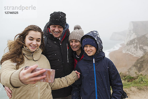 Schneefall über einer Familie  die ein Selfie mit einem Fotohandy macht