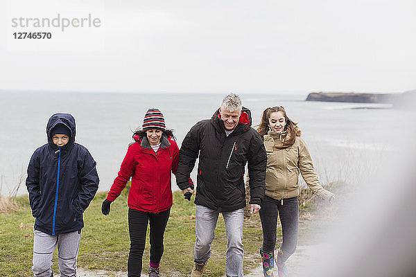 Familie in warmer Kleidung auf einer Klippe mit Blick auf das Meer