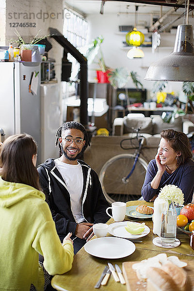 Junge erwachsene Mitbewohner und Freunde unterhalten sich am Frühstückstisch in der Wohnung