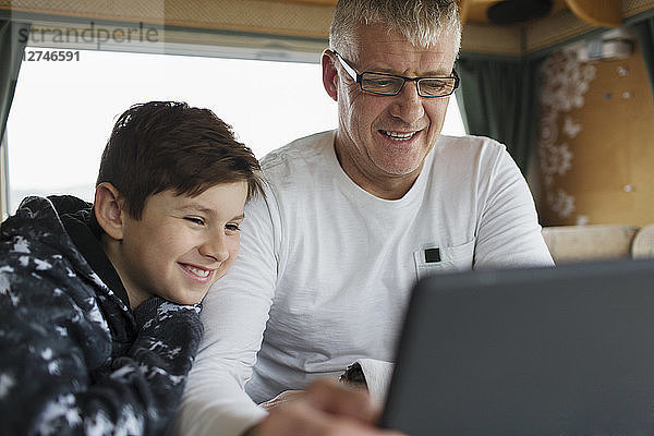 Vater und Sohn benutzen digitales Tablet im Wohnmobil